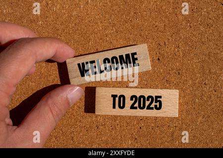 Willkommen bei 2025 Nachricht auf Holzblöcken mit braunem Hintergrund. Konzeptionelles Willkommen bei 2025 Symbol. Kopierbereich. Stockfoto