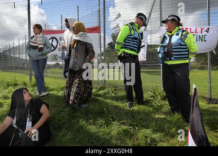 Blackburn, England, Großbritannien. August 2024. Demonstranten versammeln sich während der Demonstration vor den Haupttoren der BAE Systems-Einrichtung, die von Polizisten beobachtet wird. Demonstranten beschuldigen BAE Systems, am Völkermord in Gaza beteiligt zu sein, indem sie Teile für die F-35-Kampfflugzeuge in ihrer Anlage in Samlesbury herstellen, die beim Luftangriff auf Gaza und den Jemen eingesetzt wurden. Seit dem 10/24 wurden über 5000 Luftangriffe auf Gaza gerichtet, bei denen Tausende von Zivilisten getötet wurden, darunter 16.500 Kinder. Quelle: ZUMA Press, Inc./Alamy Live News Stockfoto