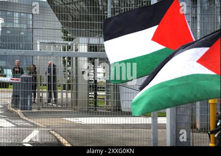 Blackburn, England, Großbritannien. August 2024. BAE-Mitarbeiter schauen durch den Zaun auf Demonstranten, die während der Demonstration palästinensische Flaggen halten. Demonstranten beschuldigen BAE Systems, am Völkermord in Gaza beteiligt zu sein, indem sie Teile für die F-35-Kampfflugzeuge in ihrer Anlage in Samlesbury herstellen, die beim Luftangriff auf Gaza und den Jemen eingesetzt wurden. Seit dem 10/24 wurden über 5000 Luftangriffe auf Gaza gerichtet, bei denen Tausende von Zivilisten getötet wurden, darunter 16.500 Kinder. Quelle: ZUMA Press, Inc./Alamy Live News Stockfoto