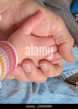 Großvater hält die Hand seiner geliebten Enkelin, während er auf dem Sofa sitzt Stockfoto