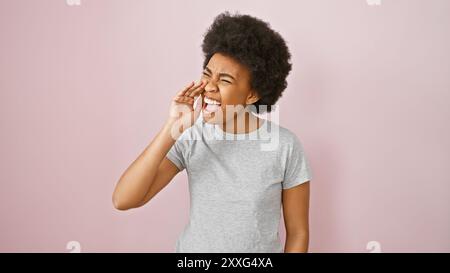 Eine afroamerikanische Frau mit lockigen Haaren, die fröhlich gegen eine rosa Wand schreit und Positivität und Kommunikation darstellt. Stockfoto