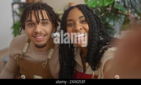 Zwei lächelnde Arbeiter, ein Mann und eine Frau, machen zusammen ein Selfie drinnen in einem Blumenladen. Stockfoto