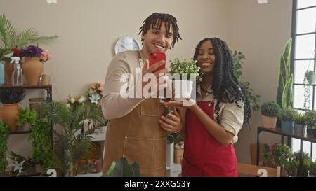 Ein Mann und eine Frau in Schürzen lächeln, während sie ein Selfie mit einer Pflanze in einem Blumenladen machen. Stockfoto