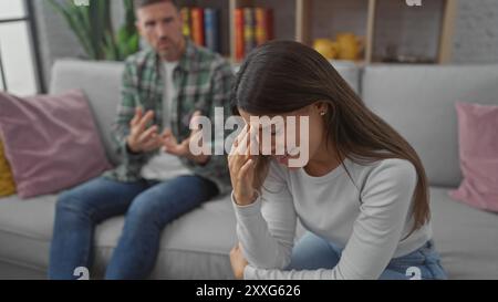 Verstörte Frau und besorgter Mann diskutieren Probleme auf dem Sofa in einem Wohnzimmer Stockfoto