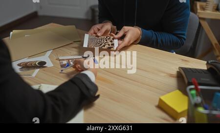 Ein Mann übergibt während einer Untersuchung in einem überfüllten Büro ein Foto, während die Inspektorin Beweise untersucht. Stockfoto