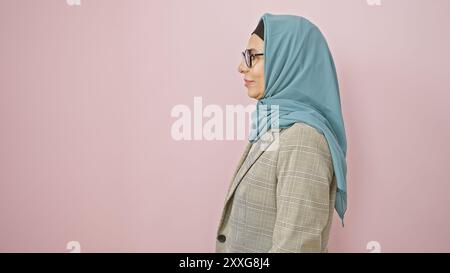 Eine reife muslimische Frau in einem Hijab auf rosa Hintergrund strahlt Selbstvertrauen und Anmut aus. Stockfoto