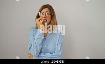 Junge Frau, die Nägel beißt mit nervöser Expression über isoliertem weißem Hintergrund Stockfoto