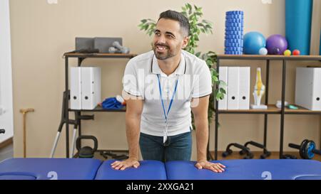 Ein lächelnder hispanischer Mann mit Bart und Lanyard in einer Physiotherapie-Klinik Stockfoto