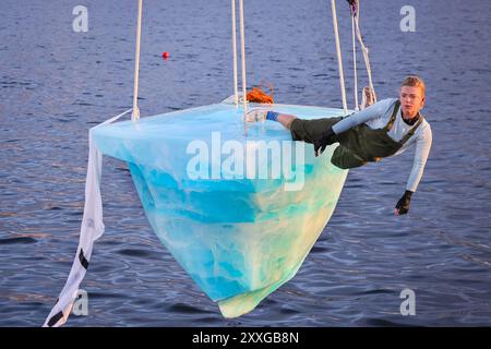 London, UK, 24. August 2024. Dritter Auftritt, Darsteller: Anna. THAW ist die europäische Premiere einer Aufführung der australischen Theatergruppe Legs on the Wall als Reaktion auf die verheerenden Buschbrände von 2019/20 und den globalen Klimawandel. Die Performance, die auf dem Docklands Campus der University of East London stattfindet, bringt die Zuschauer mit einer Performance von über 8 Stunden mit dem dringenden Bedarf an globalen Klimaschutzmaßnahmen konfrontiert und sieht einen Darsteller auf einem riesigen, 2,5 Tonnen schweren Eisblock, der an einem hohen Kran hängt. Quelle: Imageplotter/Alamy Live News Stockfoto