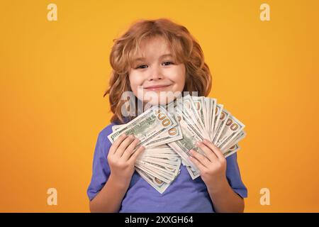 Der Junge hat viele hundert Dollar isoliert auf gelbem Hintergrund. Stockfoto