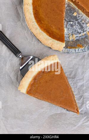 Frisch gebackene Kürbiskuchen-Scheibe auf einem Server. Hochwinkelaufnahme mit dem Rest des Kreisdiagramms im Hintergrund. Stockfoto
