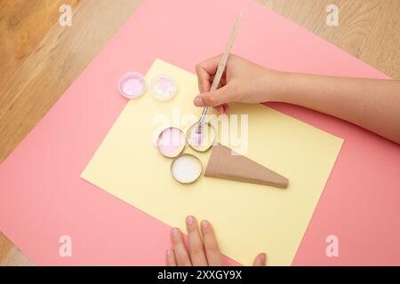 Eine Person, die einen Pinsel über ein Stück Papier hält, ein Pastell, Erdbeereis, Sommeraktivität, Farbe, Kinder, Stockfoto