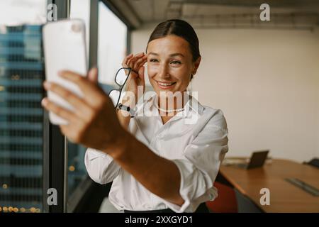 Ein modernes Büro Selfie mit einer selbstbewussten Geschäftsfrau, die Professionalität verkörpert Stockfoto