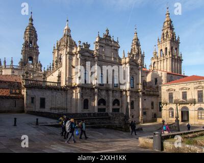 Am frühen Morgen betreten Pilger den Santiago und machen die letzten Schritte auf dem Jakobsweg mit der berühmten Kathedrale im Hintergrund. Stockfoto