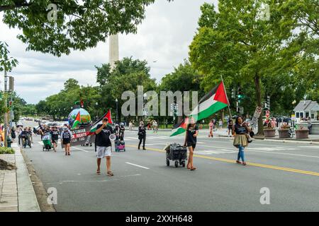 Washington DC, USA - 19.08.2024: Eine Gruppe von Menschen marschiert mit einer Palästinenserflagge die Straße hinunter. Die Flagge ist grün, weiß und rot Stockfoto