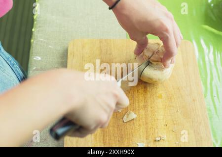 Kochen Von Pilzen. Schneiden. Weibliche Hände auf einem Schneidebrett in große Holzpilze geschnitten. Das Konzept des Kochens zu Hause. Das Konzept der Heilung Stockfoto