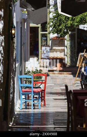 Nafplio, Griechenland Blick auf die Altstadt mit roten und blauen bunten Tisch und Stühlen in kleinen Street Cafe in Nafplion, Peloponnes Stockfoto