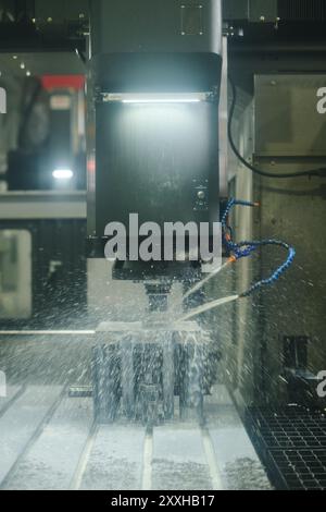 Verwendung einer CNC-Maschine für Präzisionsfräsen in einer industriellen Umgebung unter hellem künstlichem Licht, das einen hochtechnologischen Fertigungsprozess darstellt Stockfoto