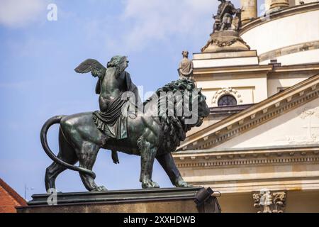 Statue eines Engels, der auf einem Löwen reitet und Harfe spielt, mit der französischen Kathedrale im Hintergrund Stockfoto