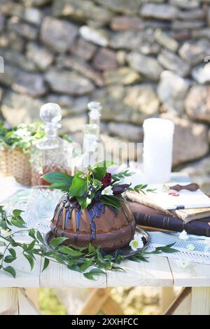 Cocolate Kuchen verziert mit Blumen und drei Whiskey Dekanter gegen einen hellgrauen Hintergrund mit Textfreiraum Stockfoto