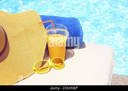 Schwimmbad, Orangensaft, Strandtuch, Sonnenbrille auf der Sonnenliege. Sommer Urlaub Konzept Stockfoto