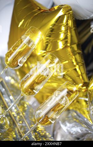 Nahaufnahme von glänzende Gläser Champagner über Schwarz, Weiß, goldenen und silbernen Ballons Hintergrund Stockfoto