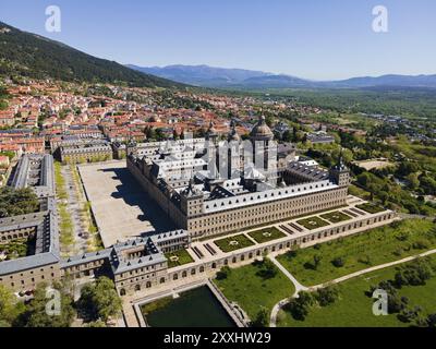 Aus der Vogelperspektive auf ein historisches Kloster und eine Stadt mit Bergen im Hintergrund an einem sonnigen Tag, aus der Vogelperspektive, Real Sitio de San Lorenzo de El Escorial, R Stockfoto