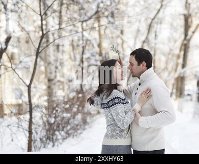 Glückliches junges Paar unter Mistel Spaß im Winter park Stockfoto