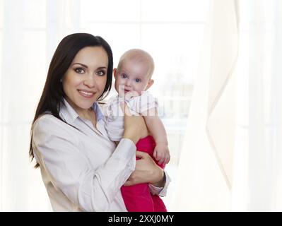 Glücklich lächelnde Mutter mit sechs Monate altes Baby Girl indoor Stockfoto