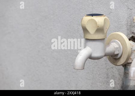 Weißer Kunststoff-Wasserhahn an der Außenwand. Stockfoto