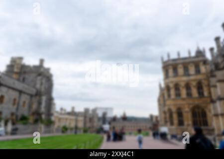 Ein verschwommenes Bild eines Innenhofs mit einem großen Gebäude im Hintergrund, mit blauem Himmel und einigen Wolken. Im Hof laufen Leute herum Stockfoto