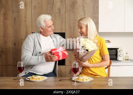 Reife Frau, die von ihrem Mann in der Küche geschenkt wird Stockfoto