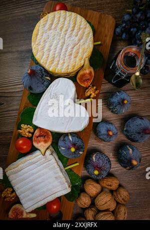 Auswahl an französischen Käsesorten aus der Normandie, AOP, Livarot, Neufchatel, Pont l'eveque, Roggenbrot, Feigen, Walnüsse, Trauben, Holundergelee Stockfoto