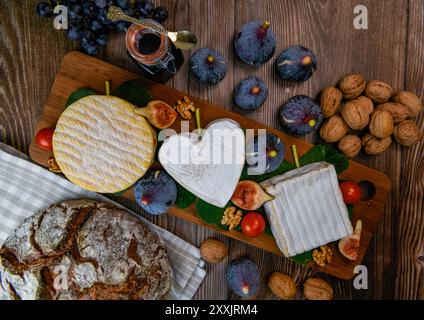 Auswahl an französischen Käsesorten aus der Normandie, AOP, Livarot, Neufchatel, Pont l'eveque, Roggenbrot, Feigen, Walnüsse, Trauben, Holundergelee Stockfoto