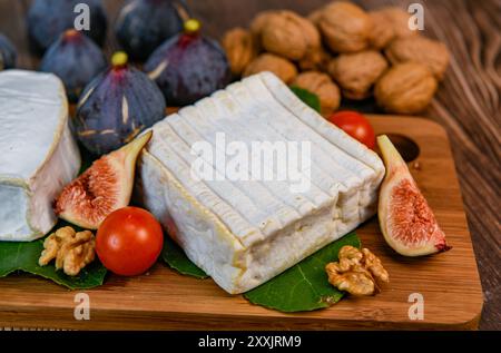 Auswahl an französischen Käsesorten aus der Normandie, AOP, Livarot, Neufchatel, Pont l'eveque, Roggenbrot, Feigen, Walnüsse, Trauben, Holundergelee Stockfoto