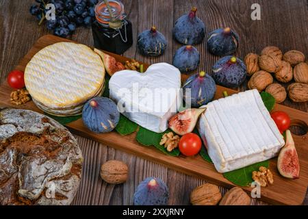 Auswahl an französischen Käsesorten aus der Normandie, AOP, Livarot, Neufchatel, Pont l'eveque, Roggenbrot, Feigen, Walnüsse, Trauben, Holundergelee Stockfoto