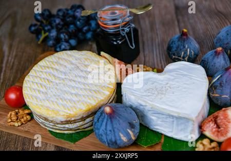 Auswahl an französischen Käsesorten aus der Normandie, AOP, Livarot, Neufchatel, Pont l'eveque, Roggenbrot, Feigen, Walnüsse, Trauben, Holundergelee Stockfoto