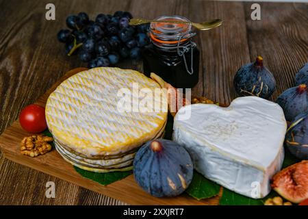 Auswahl an französischen Käsesorten aus der Normandie, AOP, Livarot, Neufchatel, Pont l'eveque, Roggenbrot, Feigen, Walnüsse, Trauben, Holundergelee Stockfoto