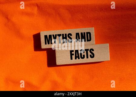 Mythen und Fakten Botschaft auf Holzblöcken mit orangefarbenem Hintergrund. Begriffliches Mythen- und Tatsachensymbol. Kopierbereich. Stockfoto