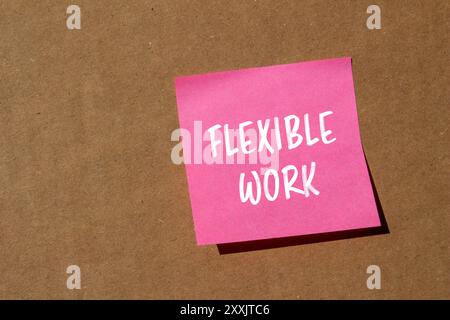 Flexible Arbeitsbotschaft auf rosafarbenem Papier mit Papphintergrund. Konzeptionelles flexibles Arbeitssymbol. Kopierbereich. Stockfoto