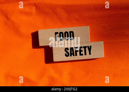 Lebensmittelsicherheitsschild auf Holzblöcken mit orangefarbenem Hintergrund. Begriffliches Symbol für Lebensmittelsicherheit. Kopierbereich. Stockfoto