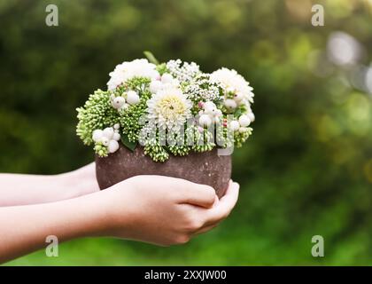 Wunderschöner Blumenstrauß aus weißer Dahlien, auffälligen Steinblumen und Schneebaumzweigen in einer rustikalen Vase in Mädchenhänden. Garten- und Inneneinrichtung Stockfoto