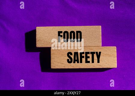 Lebensmittelsicherheitsschild auf Holzblöcken mit violettem Hintergrund. Begriffliches Symbol für Lebensmittelsicherheit. Kopierbereich. Stockfoto