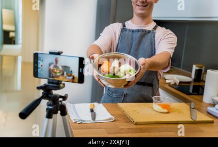 Ein Mann stellt ein veganes Rezept in einem Live-Stream in einer modernen Küche aus Stockfoto