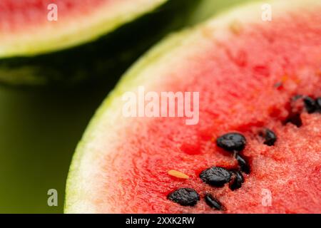 Lebendige Scheiben von Bio-Wassermelonen zeigen saftiges rotes Fruchtfleisch und kontrastierende schwarze Samen, was eine köstliche und erfrischende Sommerfrucht-Option mit reichhaltigem Fruchtangebot bietet Stockfoto