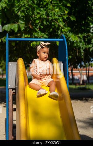 Ein Jahr altes Latina Baby auf einer Rutsche auf einem Spielplatz Stockfoto