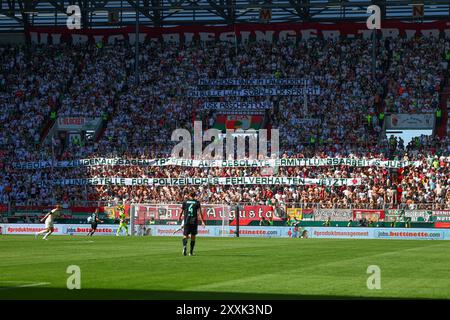 Fanblock Augsburg, „Märchenstunde im Landgericht“, Spruchband wegen dem aktuellen Polizisten-Prozeß, Schuß aus der Dienstpistole eines Polizisten vor der WWK-Arena vor etwa einem Jahr; FC Augsburg vs. Werder Bremen, 1. SPIELTAG; DFL-VORSCHRIFTEN VERBIETEN DIE VERWENDUNG VON FOTOS ALS BILDSEQUENZEN UND/ODER QUASI-VIDEO. Stockfoto