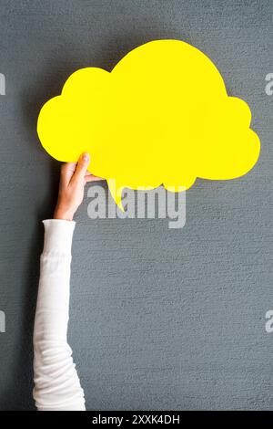 Cloud für Ihre Werbung. Nahaufnahme einer Frau, die eine leere Sprechblase vor grauem Hintergrund ausstreckt Stockfoto