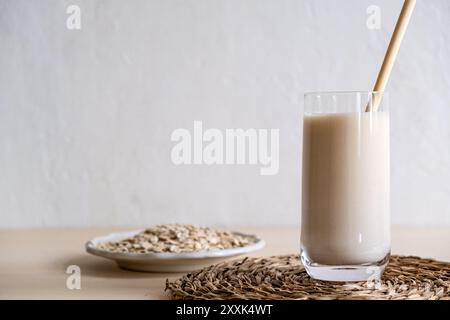 Hafermilch im Glas, Flocken von gebackenem Getreide. Milchersatz, Milch für Vegetarier. Flatlay. Speicherplatz kopieren. Stockfoto
