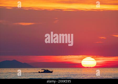 Ein kleines Fischerboot, das vor einer untergehenden Sonne in der Adria in Kroatien liegt. Stockfoto